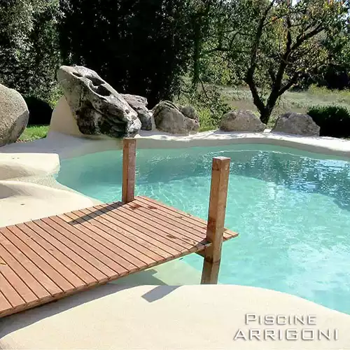 Piscina stile laghetto con superfici in sabbia
